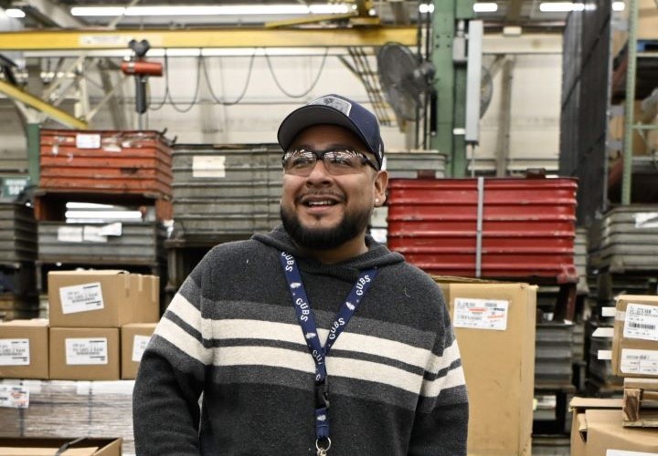 An S&C team member smiles in front of supply boxes