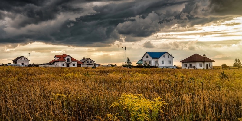 Farm houses in the field under stormy clouds