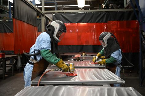 Employees fabricating industrial equipment using metalworking tools in a manufacturing facility.