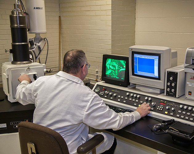Man in white lab coat sitting at S and C electrical laboratory testing for electrical equipment to see if it withstands the extremes of nature and time to ensure proper functioning of your power system Laboratory testing for electrical equipment, electrical equipment lab testing, electrical equipment laboratory testing